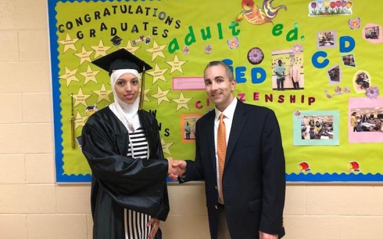 graduate Hala Mashhour shakes hands with Anthony Mangiafico