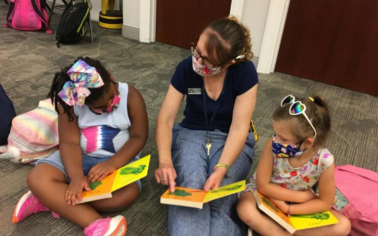 Children reading with library staff member